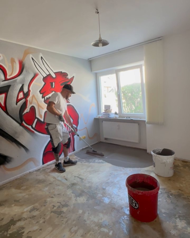 Freigelegter Untergrund mit sichtbaren Restspuren und einem Mitarbeiter beim Aufbringen der Ausgleichsmasse.